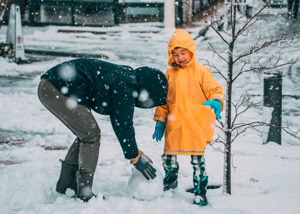 En forelder og barn som leker sammen i snøen